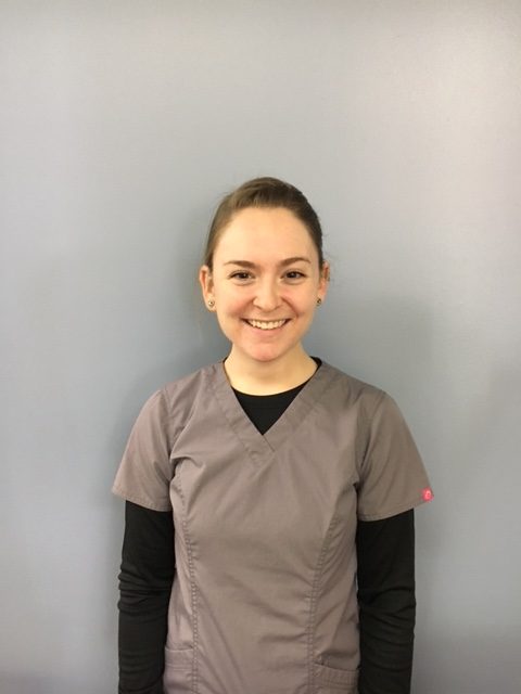 a woman in grey scrubs smiling for the camera