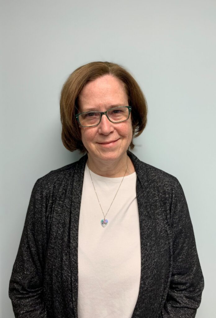 a woman wearing glasses standing in front of a wall