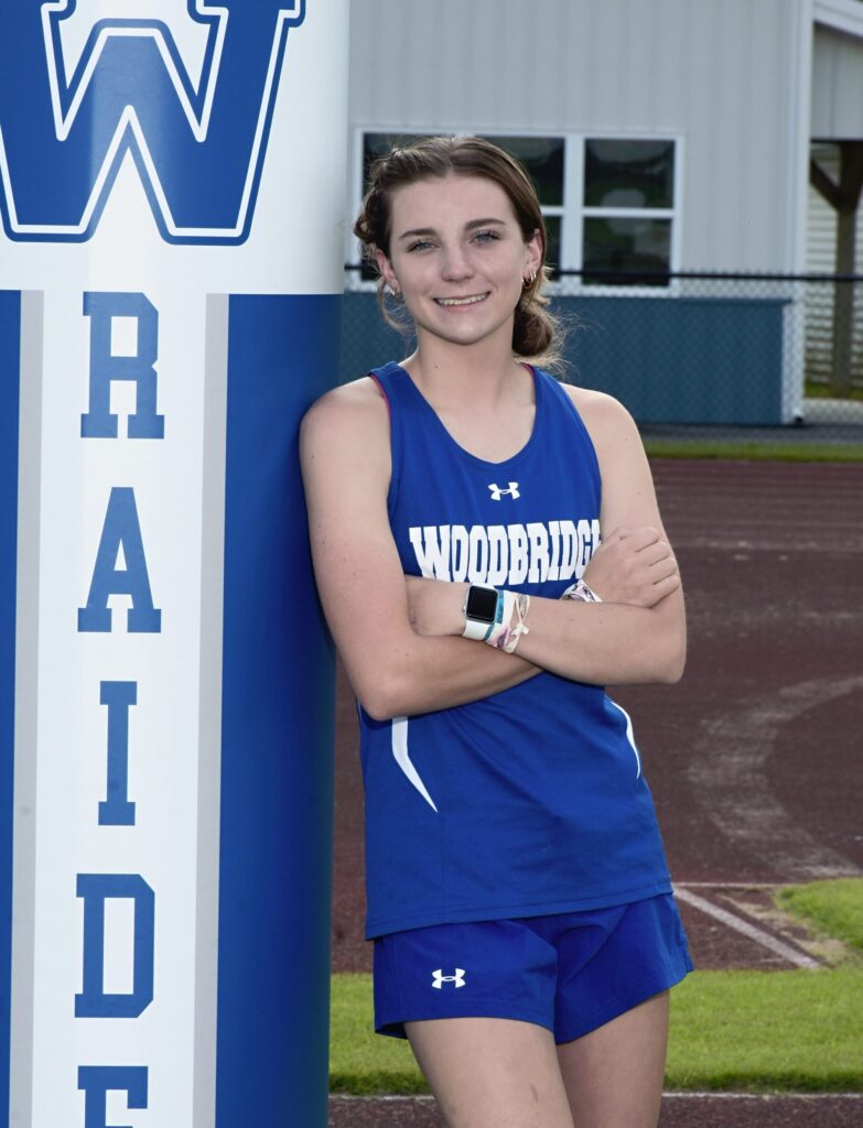 a girl standing next to a sign with her arms crossed