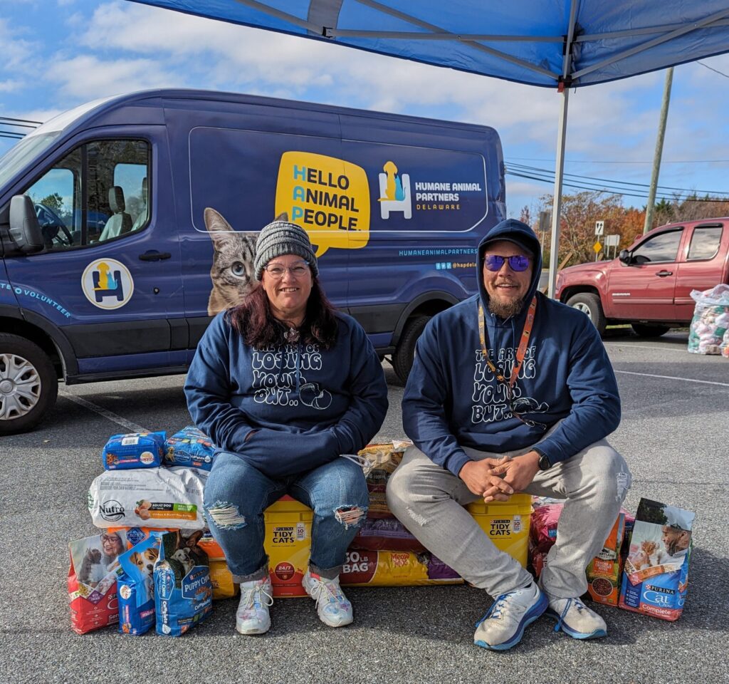 two people sitting on a bench in front of a van