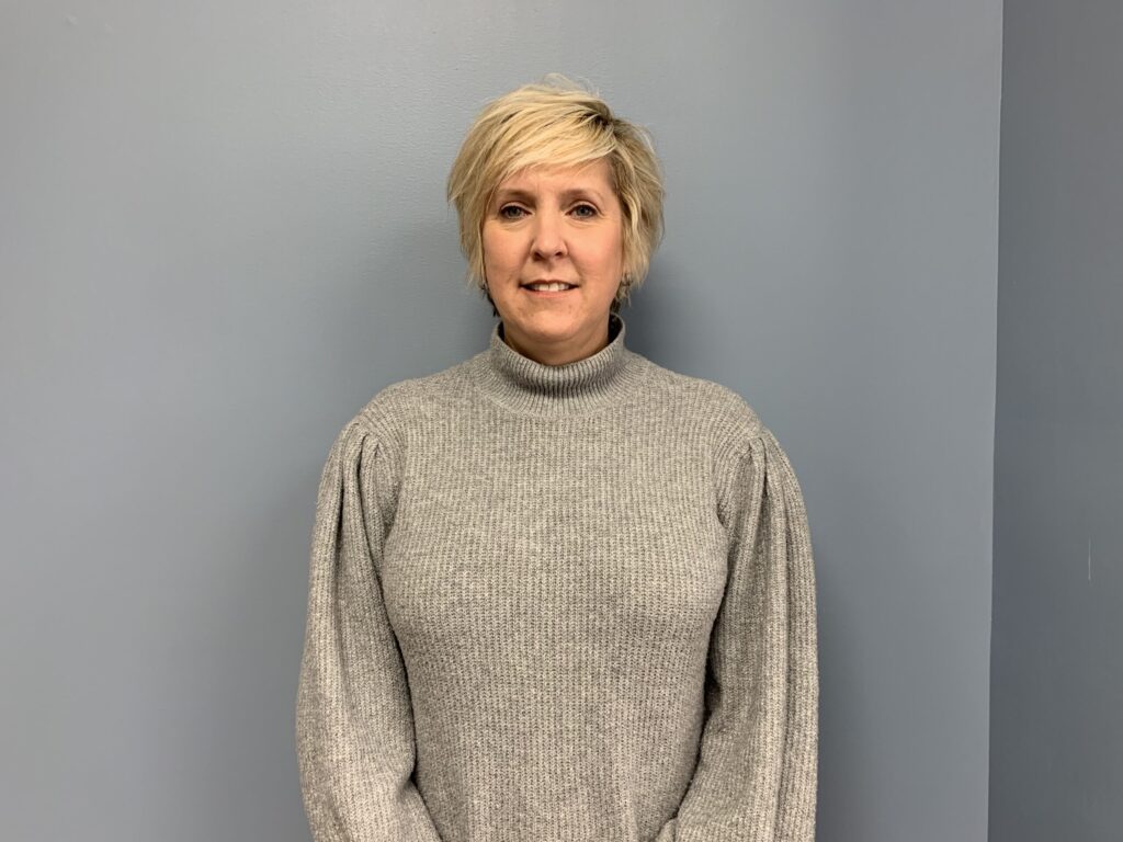 a woman standing in front of a gray wall