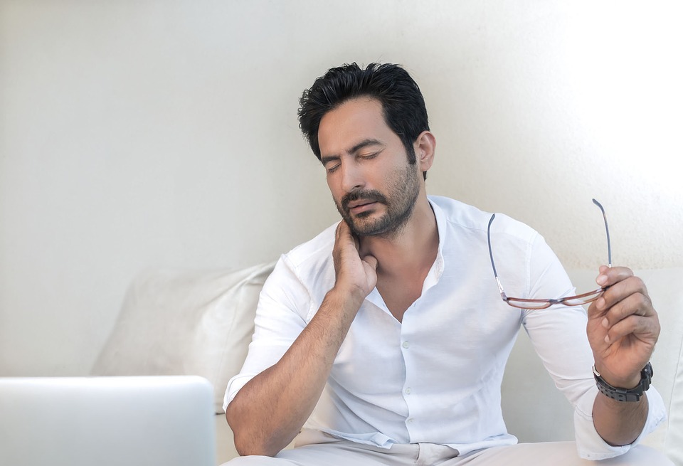 a man sitting on a couch holding a pair of glasses