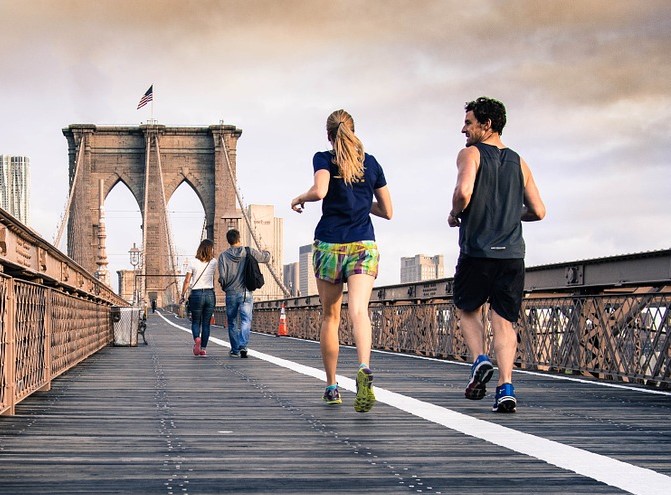 three people running across a bridge on a cloudy day