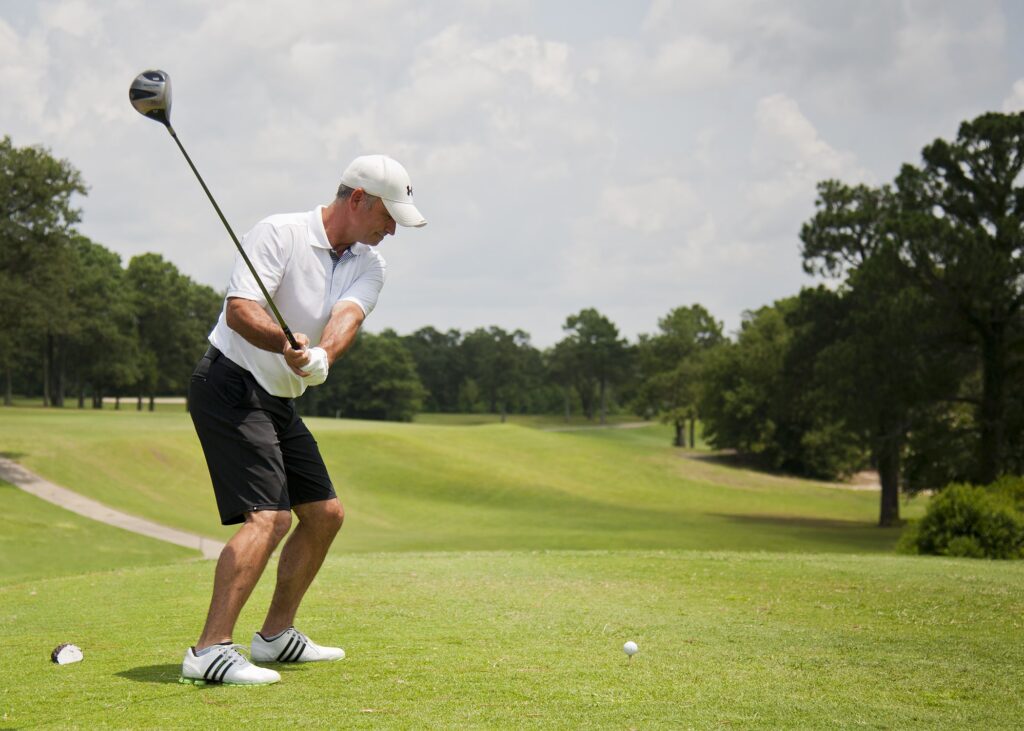 a man swinging a golf club on a green course