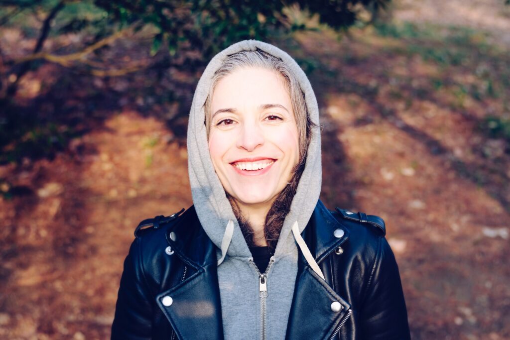 a woman wearing a black jacket and a hoodie